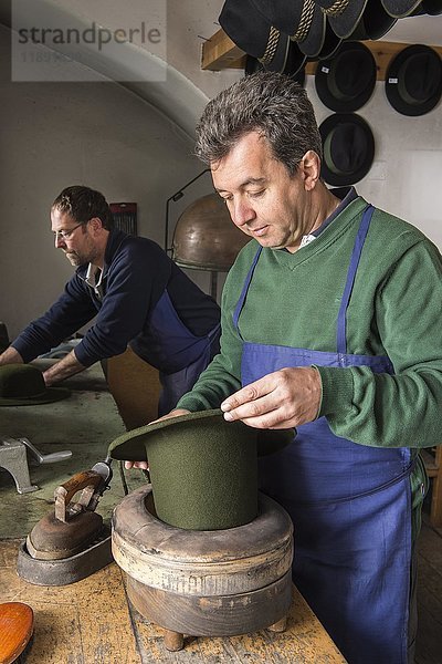 Hutmacher  der einen trockenen Wollfilzhut in einer Randform hält  Hutmacherwerkstatt  Bad Aussee  Steiermark  Österreich  Europa