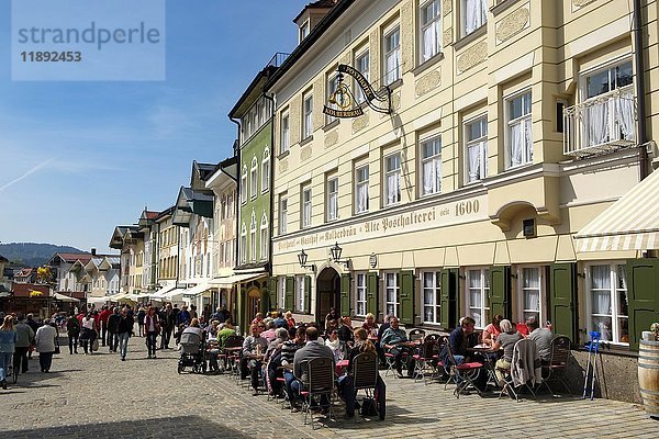 Menschen sitzen in einem Wirtshaus vor einer Reihe historischer Häuser  Marktstraße  Bad Tolz  Oberbayern  Bayern  Deutschland  Europa