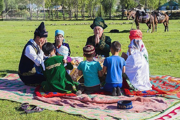 Kasachische Familie in traditioneller Kleidung beim Gebet vor dem Mittagessen  Dorf Sati  Tien-Shan-Gebirge  Kasachstan  Asien