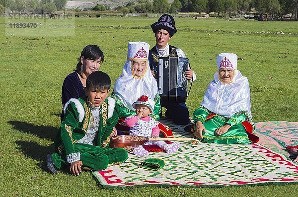 Kasachische Familie in traditioneller Kleidung lauscht der Musik eines Akkordeonspielers  Dorf Sati  Tien-Shan-Gebirge  Kasachstan  Asien