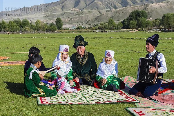 Kasachische Familie in traditioneller Kleidung lauscht der Musik eines Akkordeonspielers  Dorf Sati  Tien-Shan-Gebirge  Kasachstan  Asien