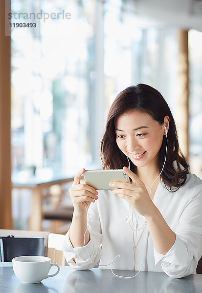 Japanische Frau mit Smartphone in einem schicken Cafe