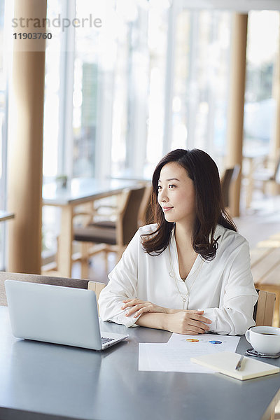 Japanische Frau mit Laptop in einem stilvollen Cafe
