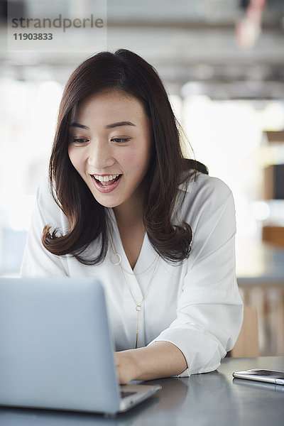 Japanische Frau mit Laptop in einem stilvollen Cafe