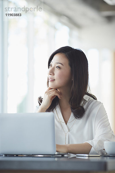 Japanische Frau mit Laptop in einem stilvollen Cafe