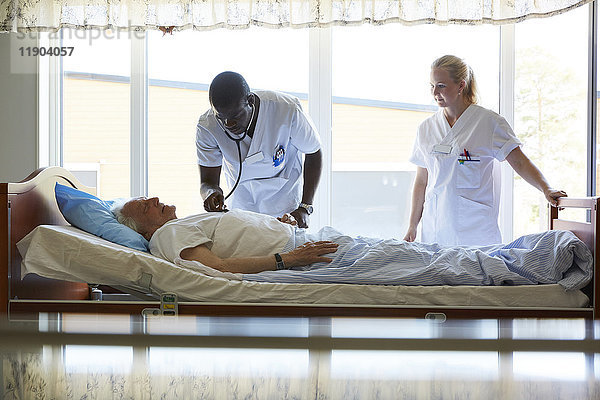 Krankenschwester bei der Untersuchung eines älteren Mannes auf dem Bett in der Krankenstation
