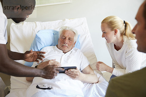 Krankenpfleger zeigt digitales Tablett für Senioren und Paare auf der Krankenstation