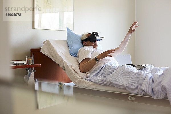 Seniorengestik bei der Verwendung der VR-Brille auf dem Bett in der Krankenstation