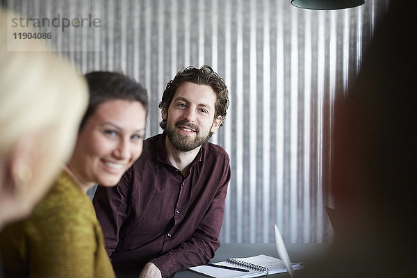 Lächelnde kreative Geschäftskollegen diskutieren im Vorstandszimmer im Büro