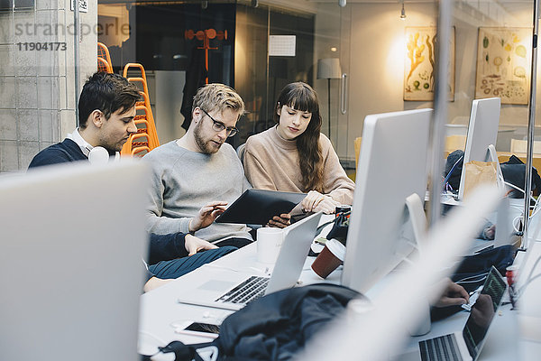 Programmierer und Programmiererinnen mit digitalem Tablett am Schreibtisch im Büro