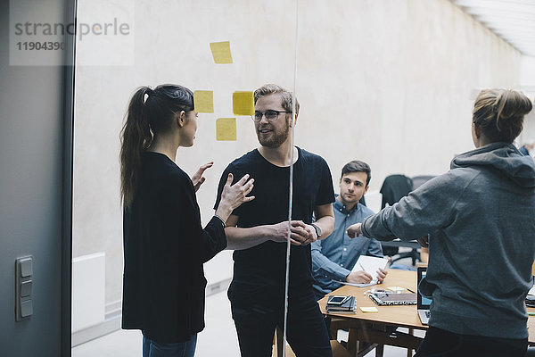 Computerprogrammierer diskutieren im Büro durch Glas gesehen