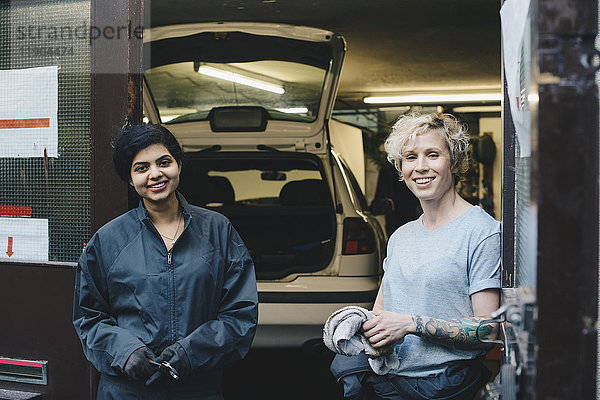 Portrait von Mitarbeiterinnen am Eingang der Autowerkstatt