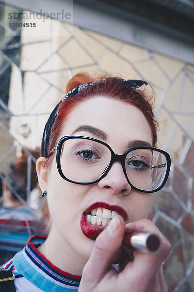 Porträt der rothaarigen jungen Frau mit rotem Lippenstift an der Mosaikwand