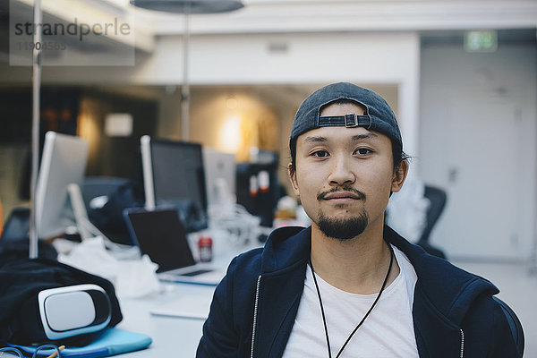 Porträt eines selbstbewussten Programmierers mit Kappe im Büro