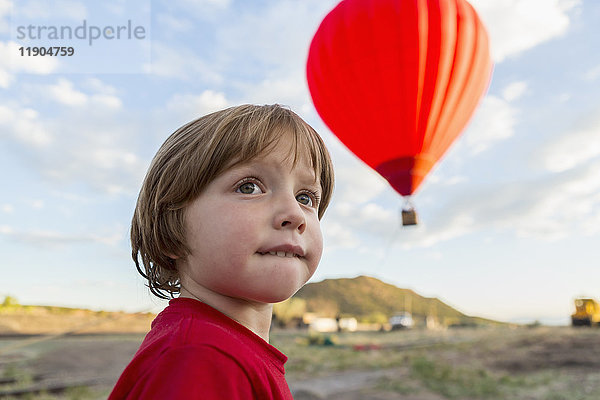 Kaukasischer Junge unter entferntem Heißluftballon