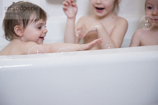Lächelnder kaukasischer Junge und Mädchen spielen in der Badewanne