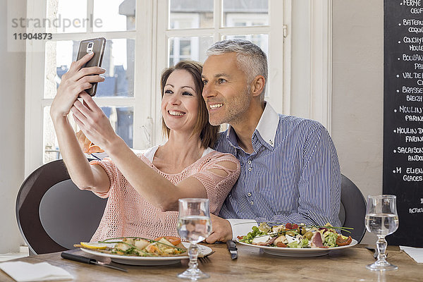 Kaukasisches Paar posiert für Handy-Selfie im Restaurant