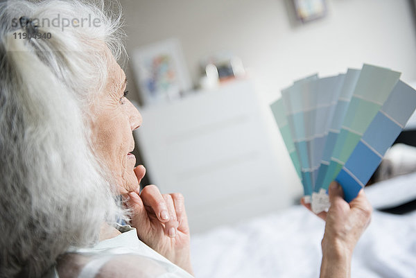 Nachdenkliche ältere Frau  die Farbmuster untersucht