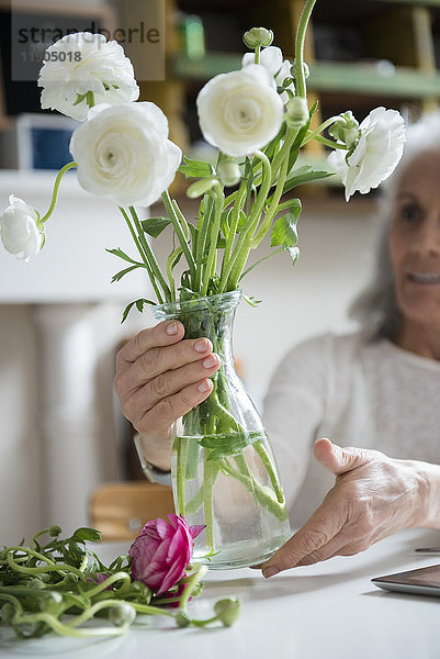 Ältere Frau arrangiert Blumen