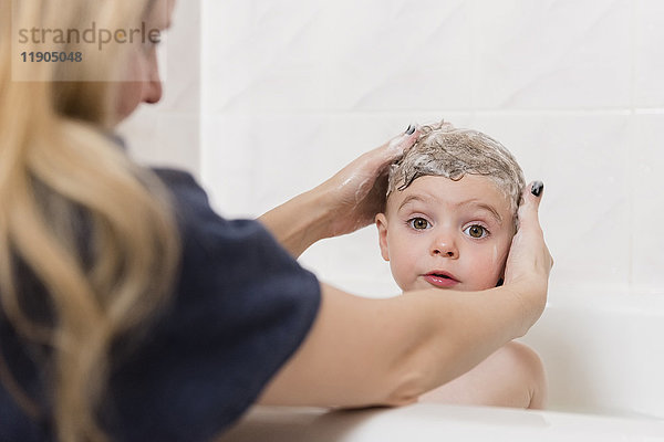 Kaukasische Mutter wäscht Haare eines Mädchens in der Badewanne