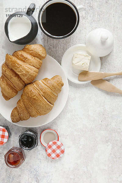 Croissants auf Teller mit Kaffee und Marmelade