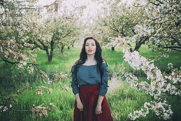 Kaukasische Frau steht in der Nähe von blühenden Bäumen