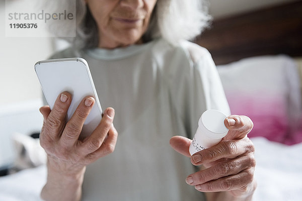 Ältere Frau prüft Rezept mit Mobiltelefon