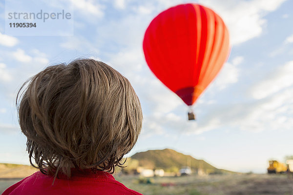 Kaukasischer Junge beobachtet fernen Heißluftballon