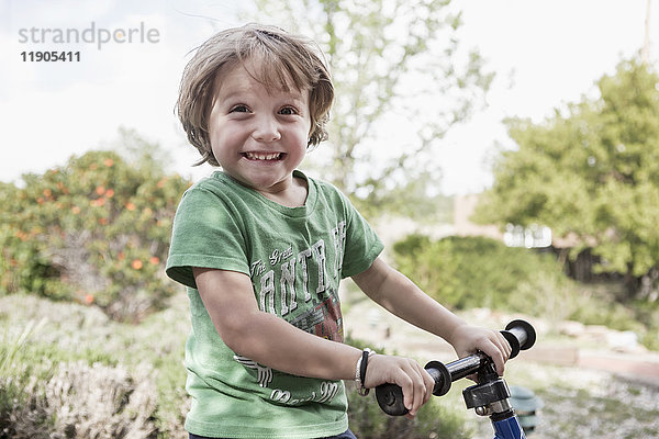 Porträt eines aufgeregten kaukasischen Jungen  der einen Lenker hält