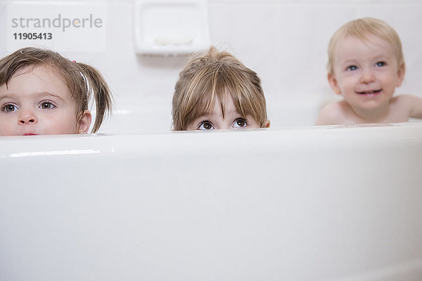 Kaukasischer Junge und Mädchen  die aus der Badewanne gucken