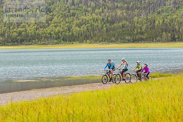 Ehepaar mit Sohn und Tochter fahren in der Nähe des Sees Fahrrad