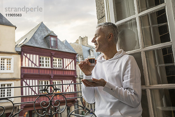 Kaukasischer Mann genießt Espresso auf einem Balkon in der Stadt