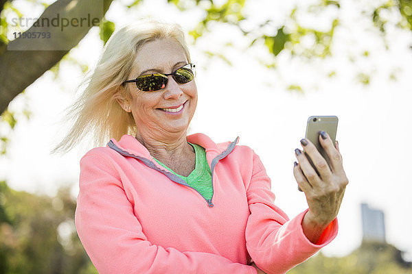 Wind weht Haare der kaukasischen Frau Texting auf Handy