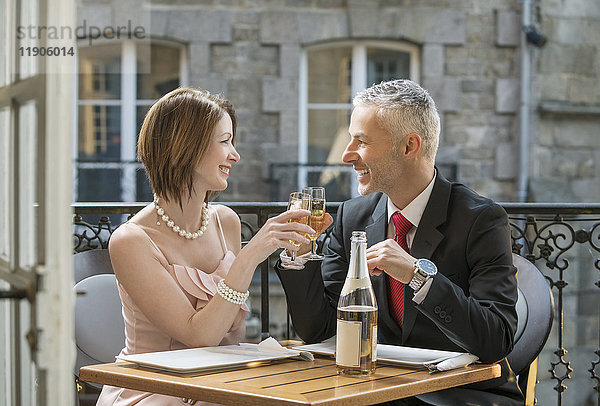 Gut gekleidetes kaukasisches Paar stößt mit Champagner an