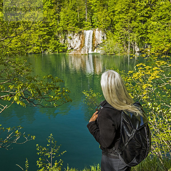 Ältere kaukasische Frau bewundert Wasserfall