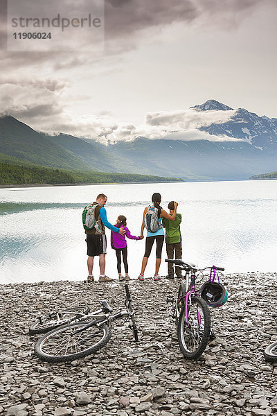 Ehepaar mit Sohn und Tochter fahren in der Nähe des Sees Fahrrad