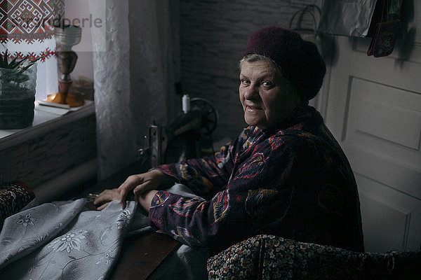 Ältere kaukasische Frau an der Nähmaschine
