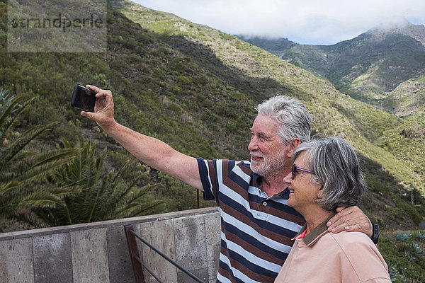 Ältere kaukasische Paare  die für ein Selfie mit dem Handy posieren