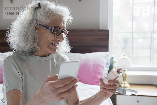 Ältere Frau prüft Rezept mit Mobiltelefon