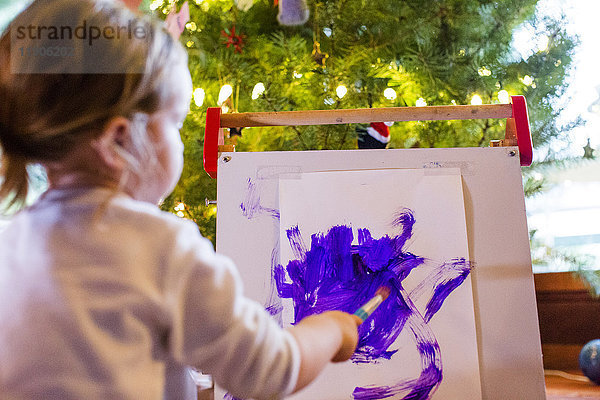 Kaukasisches Mädchen malt mit lila Farbe auf Papier