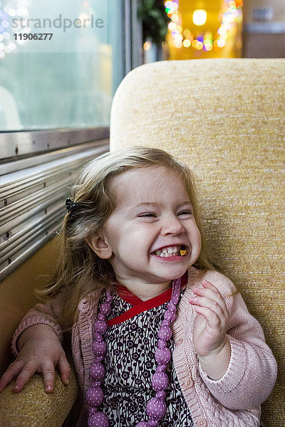 Kaukasisches Mädchen grinst am Fenster im Zug