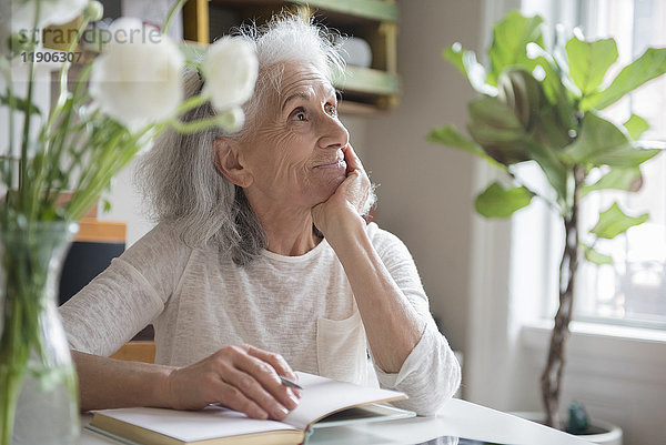 Nachdenkliche ältere Frau schreibt in ein Tagebuch
