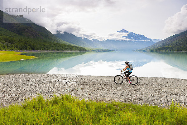Gemischtrassige Frau fährt Fahrrad in der Nähe eines Sees
