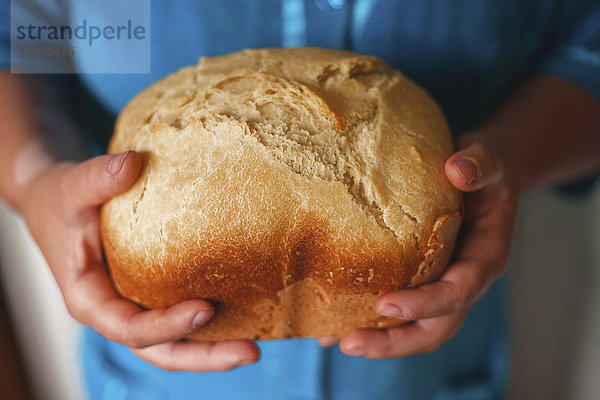 Hände halten einen Laib Brot