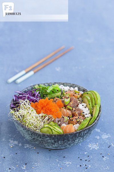 Eine Poke-Schale mit Wakame-Algen  Thunfisch  Sushi-Reis  Lachs  Alfalfa-Sprossen  Rotkohl  Sesam  Gurkenscheiben  Frühlingszwiebeln  Avocado und Tobiko