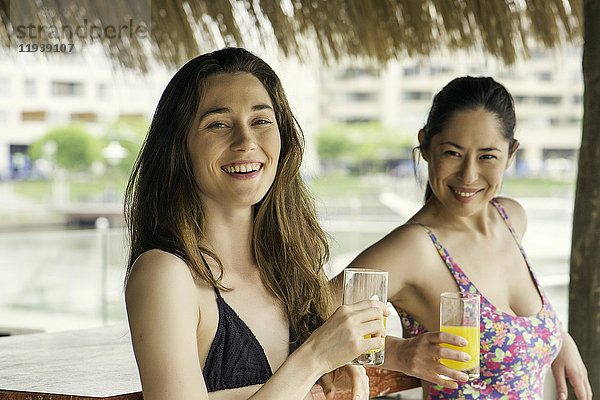 Frauen trinken Saft in der Cabana neben dem Schwimmbad