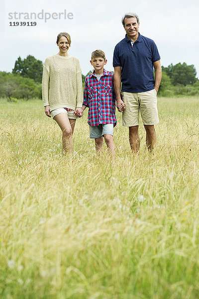 Familie mit einem Kind beim gemeinsamen Spaziergang auf freiem Feld