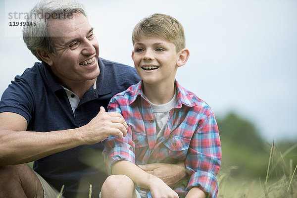 Vater und Sohn lachen gemeinsam im Freien.