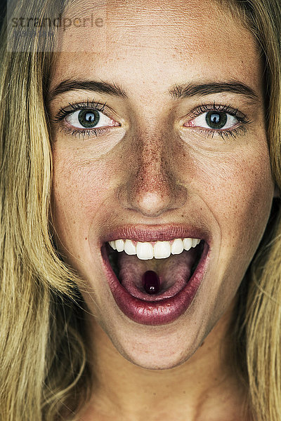 Junge Frau mit Gelkapsel auf der Zunge  Portrait