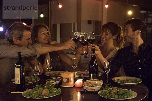 Freunde klirren auf der Dinnerparty mit Weingläsern.